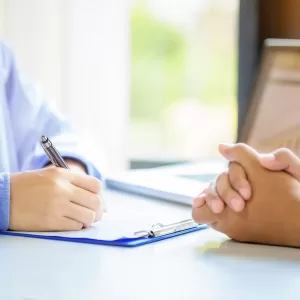 Doctor man consulting patient while filling up an application form at the desk in hospital. Medicine and health care concept